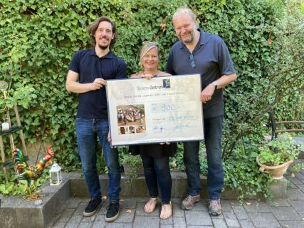 Von links nach rechts: Christian Hagen, Hannah Stuhler und Gunter Lorenz halten gemeinsamen einen übergroßen symbolischen Spendenscheck in der Hand. Darauf ist die Spendensumme von 900 Euro eingetragen.