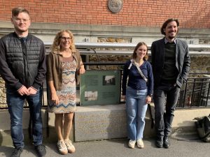 Jannis Fischer, Corina Petersilka, Nilufar Estiry und Christian Hagen stehen neben einer Gedenktafel zu Ehren von Pierre und Marie Curie