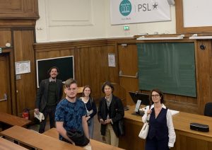 Christian Hagen, Jannis Fischer und Nilufar Estiry von der FAU, sowie Linda Koiran und Daria Moreau von der PSL stehen in einem Hörsaal der Pariser Universität. 