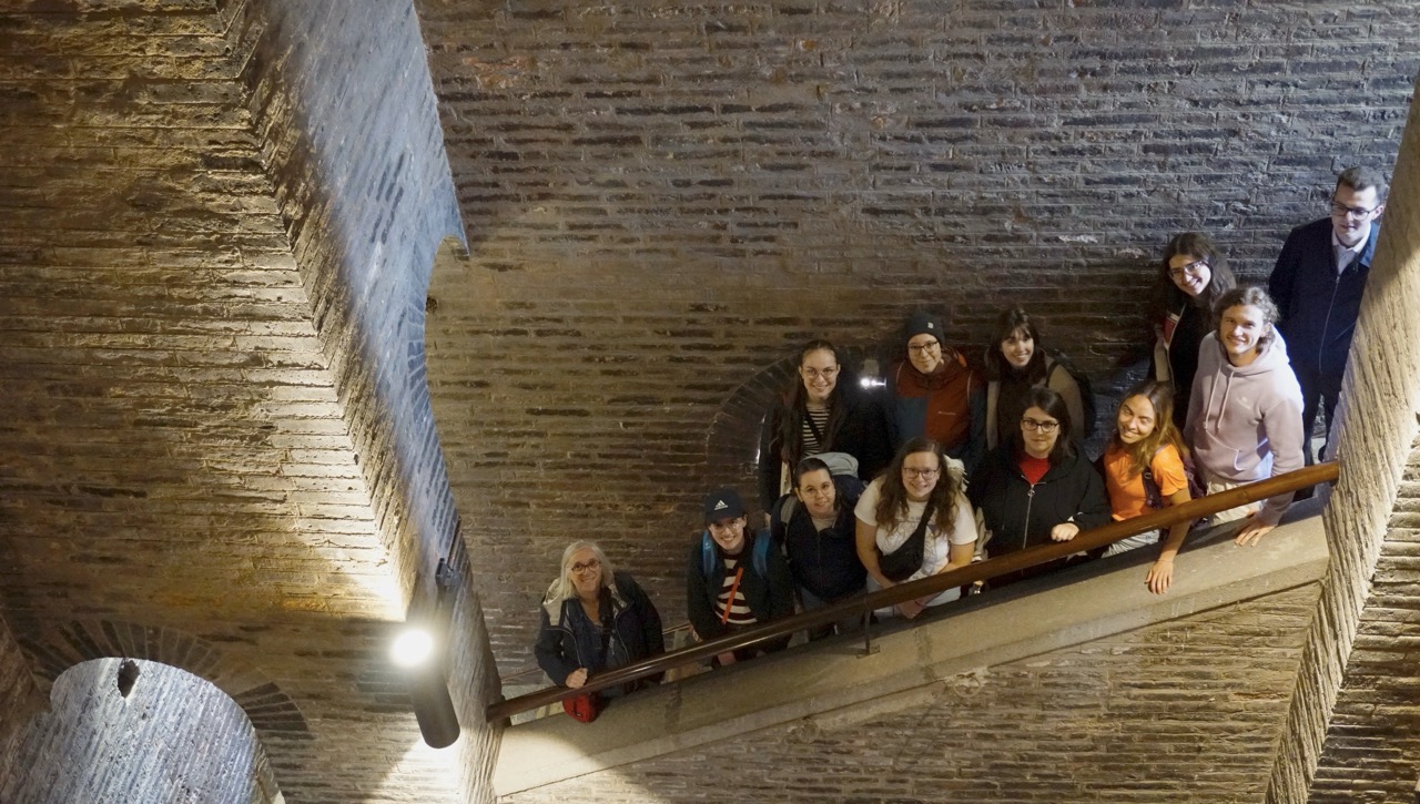 Gruppe im Backstein-Treppenhaus des Ghirlandina-Turms blickt nach oben.
