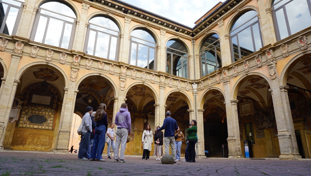 Gruppe im Arkadenhof des Archiginnasio mit verzierten Wappen.