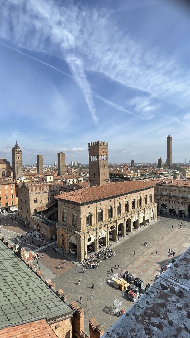 Blick von oben auf Piazza Maggiore mit Türmen von Bologna und Arkadengebäuden.
